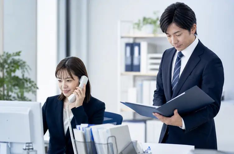 事務局への電話対応と書類確認を行う事務所のスタッフ